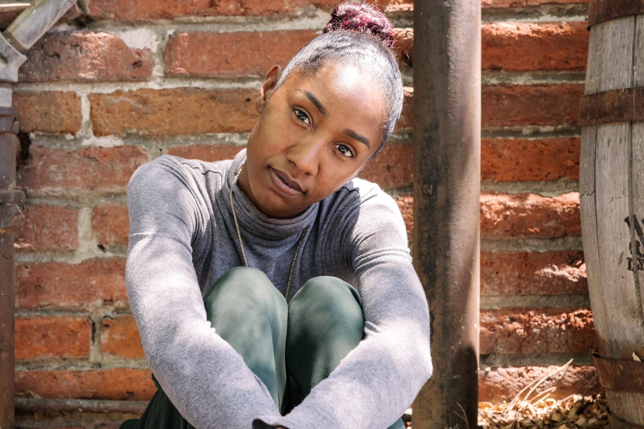 young black woman from foster care sitting in front of brick wall