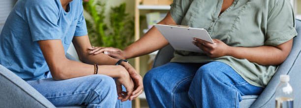 African psychologist supporting depressed teenage boy during on-site therapy