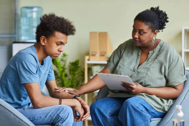 African psychologist supporting depressed teenage boy during on-site therapy