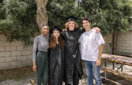 young adults in graduation gowns and caps with their supportive friends