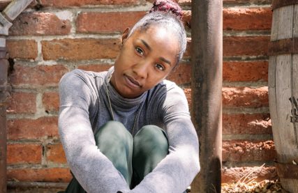 young black woman from foster care sitting in front of brick wall