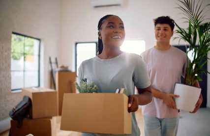 Happy black woman carrying cardboard box